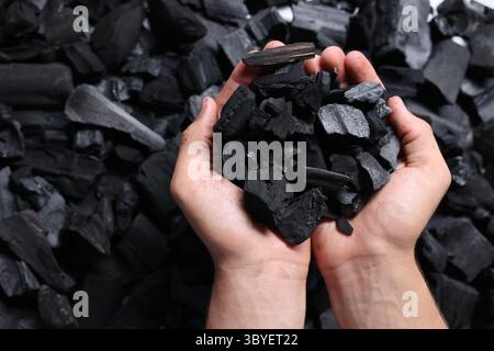 Man with black coals over pile, top view Stock Photo