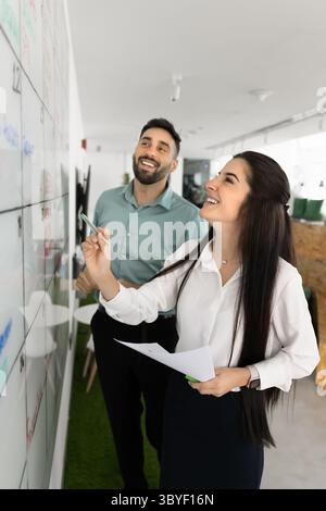 Smiling colleagues collaborating on large whiteboard calendar in office Stock Photo