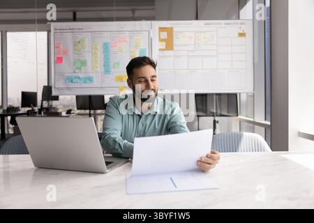 Smiling Hispanic man reviewing documents or financial report Stock Photo