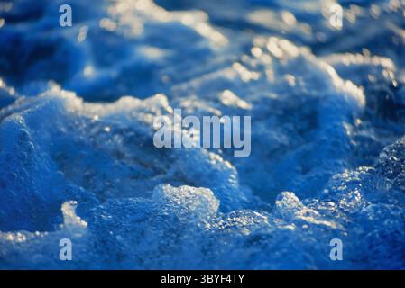 Close-up of cold blue water texture with dynamic bubbles and waves, illuminated by gentle light Stock Photo