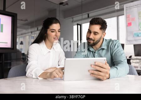 Two Latin teammates working on joint task using digital tablet Stock Photo