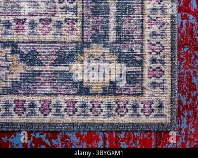 The corner of a worn antique run on a red wooden floor Stock Photo