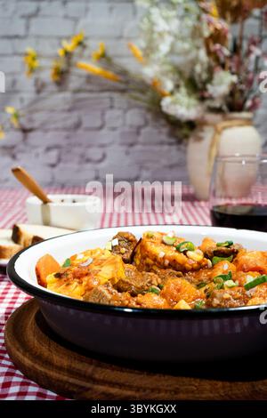 Hearty beef stew with vegetables, simmering in a rich tomato sauce, garnished with fresh spring onions Stock Photo