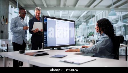 Multiracial Team Using Online Accounting Software To Calculate Invoices Together Stock Photo