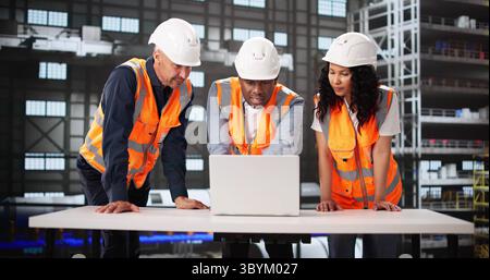 Diverse Engineering Team Using Laptop Screen At Rocket Manufacturing Facility. Stock Photo