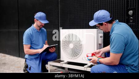 Commercial HVAC Worker Inspecting Air Conditioning System For Repairs In Building. Stock Photo