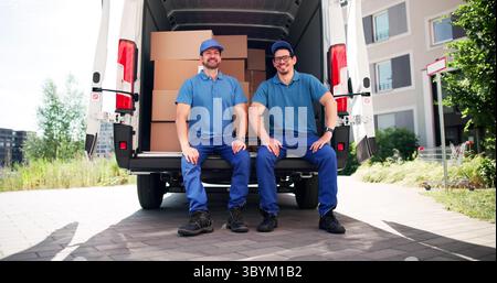 Professional Mover Team Unloading Boxes From Van Into House Stock Photo