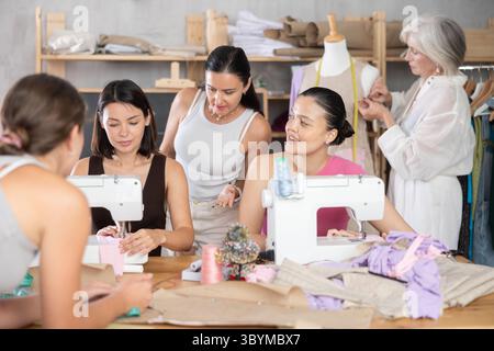 Group of women enjoying teamwork during hands-on dressmaking class Stock Photo