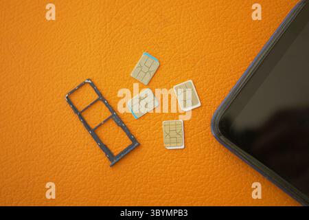SIM card tray and multiple SIM cards on an orange surface Stock Photo