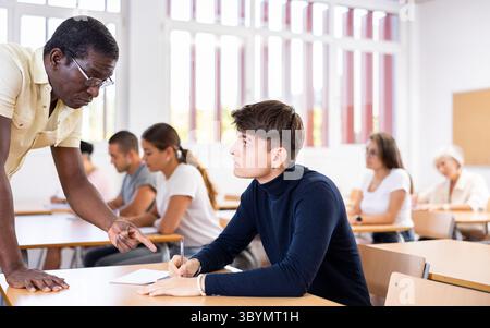 African American teacher helping student solve task during lesson Stock Photo