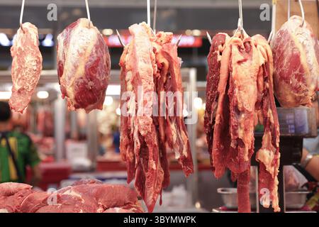 Various cuts of beef are hung on hooks. Different cuts of beef are displayed for customers to choose from. Stock Photo