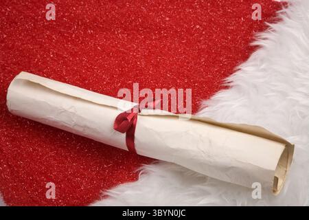 Vintage Christmas scroll tied with red ribbon on a red and white Santa hat Stock Photo