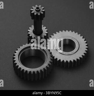 A black and white photograph showcases a complex mechanical system consisting of two gears and a connecting shaft. A large, coarse gear is positioned Stock Photo