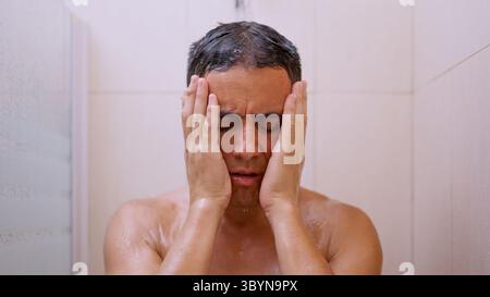Sad man covering his face with hands while taking a shower Stock Photo