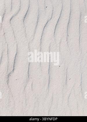 Abstract minimalist background of white sand texture. A natural pattern of soft waves and ripples created by wind. Top view. Stock Photo