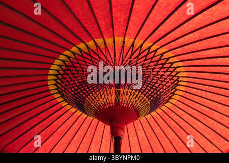 A Japanese red umbrella with yellow and blue accents. The umbrella is open and the colors are vibrant. Concept of warmth and happiness. It is a close Stock Photo