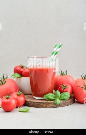 Tomato juice in a glass and fresh tomatoes on light background Stock Photo