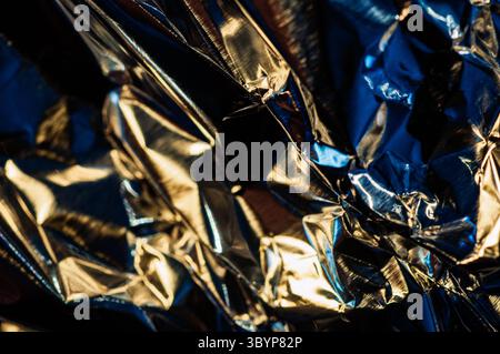 A close-up shot reveals the intricate folds and shimmering surfaces of crumpled aluminum foil. The play of light and shadow creates a dynamic texture Stock Photo