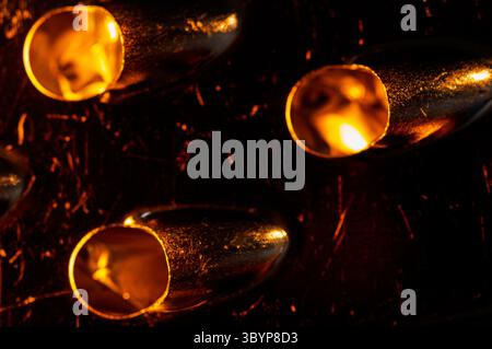 A macro shot of a metal grater, focusing on the sharp grating holes. Light reflects off the metal, creating a warm, abstract pattern Stock Photo