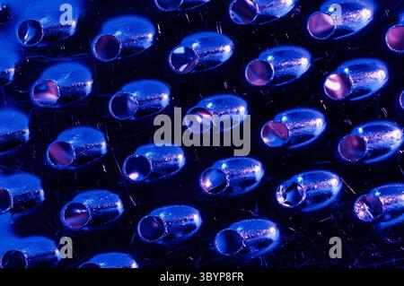 A close-up, abstract view of a cheese grater, illuminated with blue and purple lighting Stock Photo