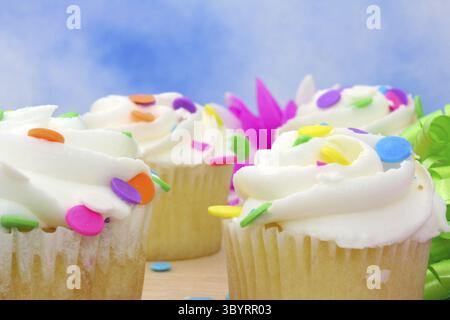 Cupcakes with brightly colored sprinkles on blue background Stock Photo