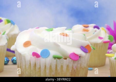 Cupcakes with brightly colored sprinkles on blue background Stock Photo