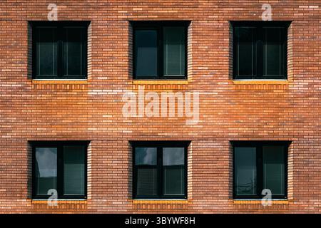 Simple brick apartment wall with symmetrical black-framed windows Stock Photo
