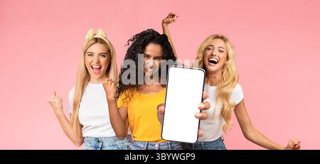 Carefree millennial ladies having fun, showing smartphone, mockup Stock Photo