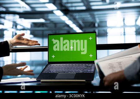 System administrators in data center using chroma key green screen laptop, refining server virtualization strategies. Teamworking server hub coworkers using mockup notebook to configure cluster nodes Stock Photo