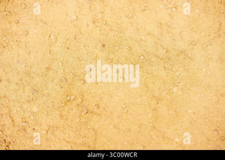 Dry ochre soil studded with weathered pebbles and fine sediment revealing intricate granular patterns under soft natural light Stock Photo