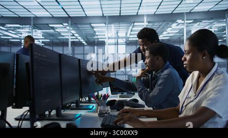 Manager supervising server room workers developing disaster recovery plans ensuring minimal downtime. Supervisor oversees data center technicians using data analytics to monitor performance, camera A Stock Photo