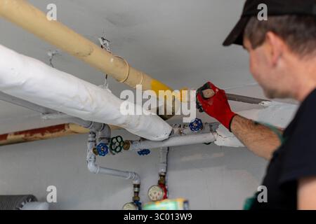 A skilled plumber is currently working diligently on various pipes within a residential setting Stock Photo