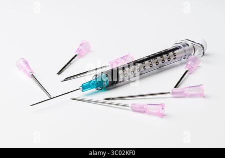 Medical syringe with blue needle and multiple pink needles on white background Stock Photo