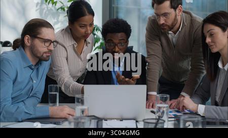 Multiethnic business team women men teamwork in office desk talking planning discuss laptop online project company corporate work colleagues Indian Stock Photo