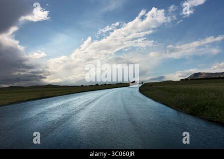 asphalt road reflecting the sky after the rain in Sicily, Italy Stock Photo
