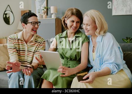 Three Middle Aged Caucasian Women Smiling While Using Digital Tablet Together Stock Photo