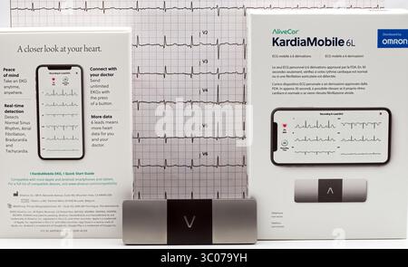 A portable Alivecor Kardiamobile 6L by Omron. Personal EKG device is shown with its packaging and an ECG waveform pri Stock Photo