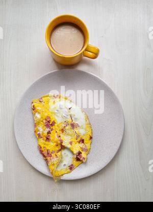 Breakfast with coffee. Yellow cup of coffee and yellow omelette on a beige plate. Stock Photo