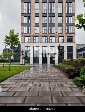 Footpath leading to modern office building. Small park near business center with benches and green trees. Stock Photo