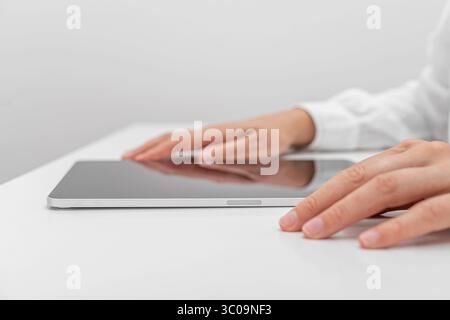 A person in a white shirt interacts with a tablet. Stock Photo