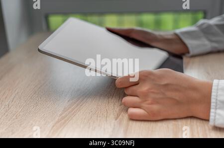 A person in a white shirt interacts with a tablet. Stock Photo