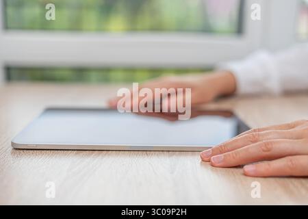 A person in a white shirt interacts with a tablet. Stock Photo