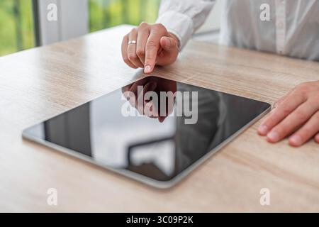 A person in a white shirt interacts with a tablet. Stock Photo