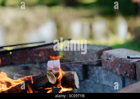 Roasting marshmallows at a lakeside brick fire pit at sunset Stock Photo