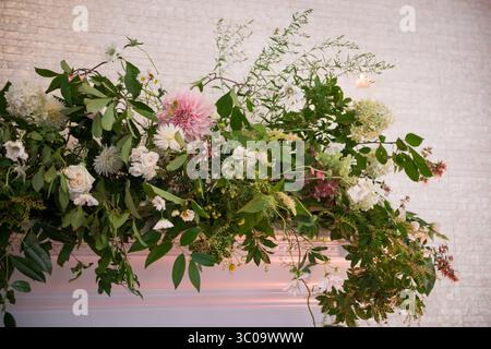 Lush Green and Floral Wedding Installation Against White Brick W Stock Photo