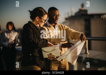 Diverse business colleagues collaborating during sunset on high tower balcony Stock Photo