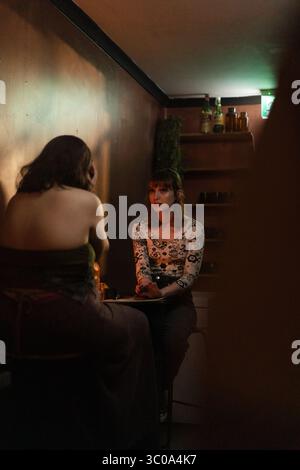 Intimate conversation between two women in a dimly lit bar corner Stock Photo