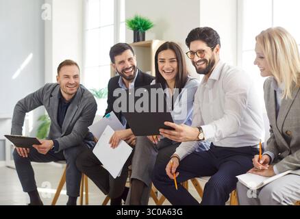 Group of cheerful business people discussing work documents during team meeting in office. Stock Photo