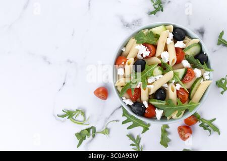 Mediterranean Pasta Salad in bowl with Fresh Vegetables and Herbs on marble background Stock Photo