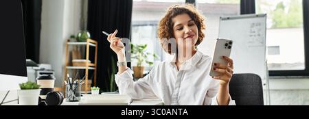 Curly-haired businesswoman enjoys her workday while using her smartphone at a stylish office, banner Stock Photo